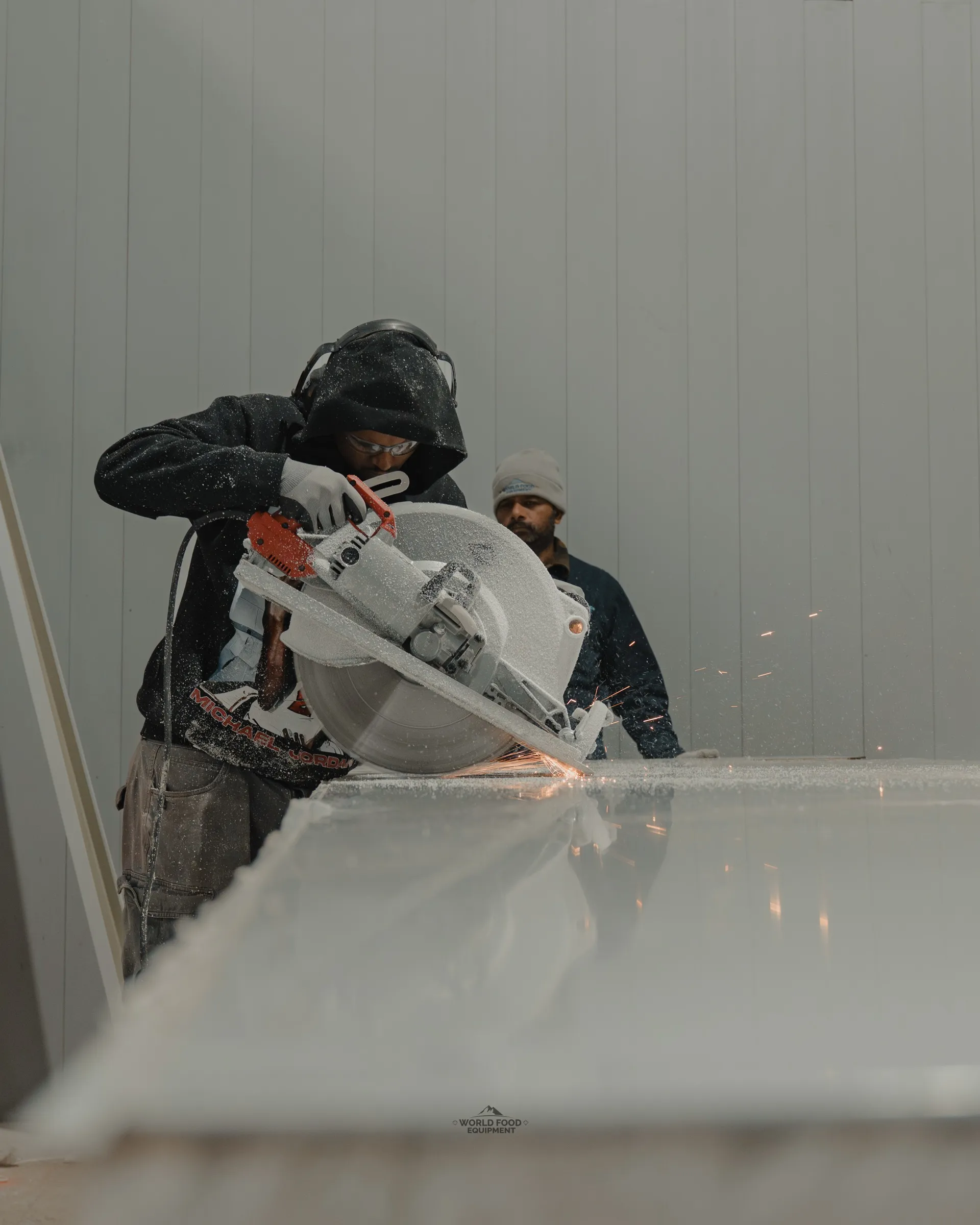 WFE worker cutting an insulated panel with a circular saw at the 35 Silton walk-in cold storage build, sparks flying. Every panel cut on site to fit the actual dimensions of an existing commercial space.