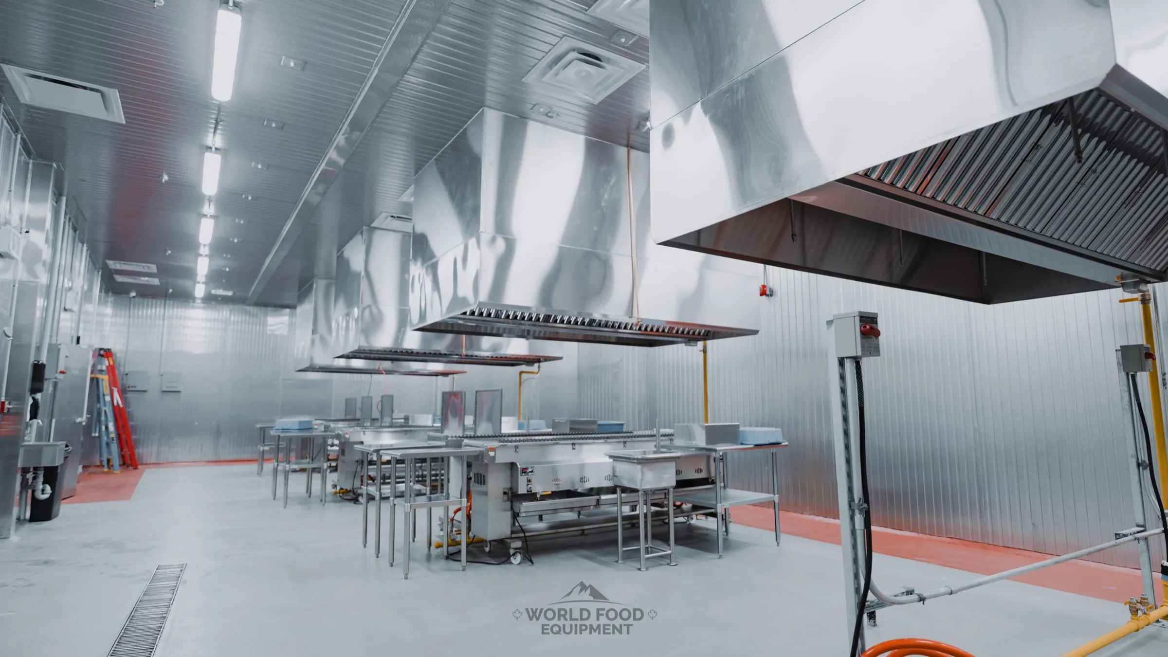 Interior view of an Al Shamas commercial restaurant kitchen with stainless steel prep tables, halal meat hooks at the wall, white insulated panel walls and ceiling, polished floor, Ontario commercial restaurant refrigeration installation by World Food Equipment