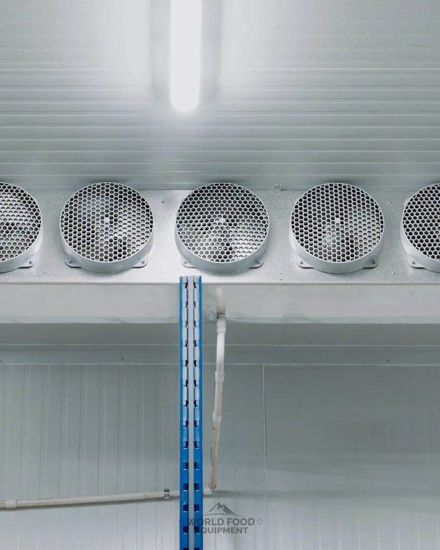 Trenton five-fan ceiling-mounted evaporator unit on white insulated panel wall in a finished industrial cold storage room, Atlas Foods install, Ontario, World Food Equipment