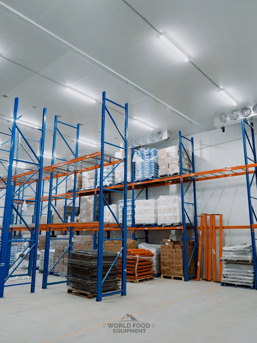 Custom cold-storage room with blue pallet racking, orange load beams, ceiling-mounted evaporators, and stored product, Atlas Foods install, Ontario, World Food Equipment.