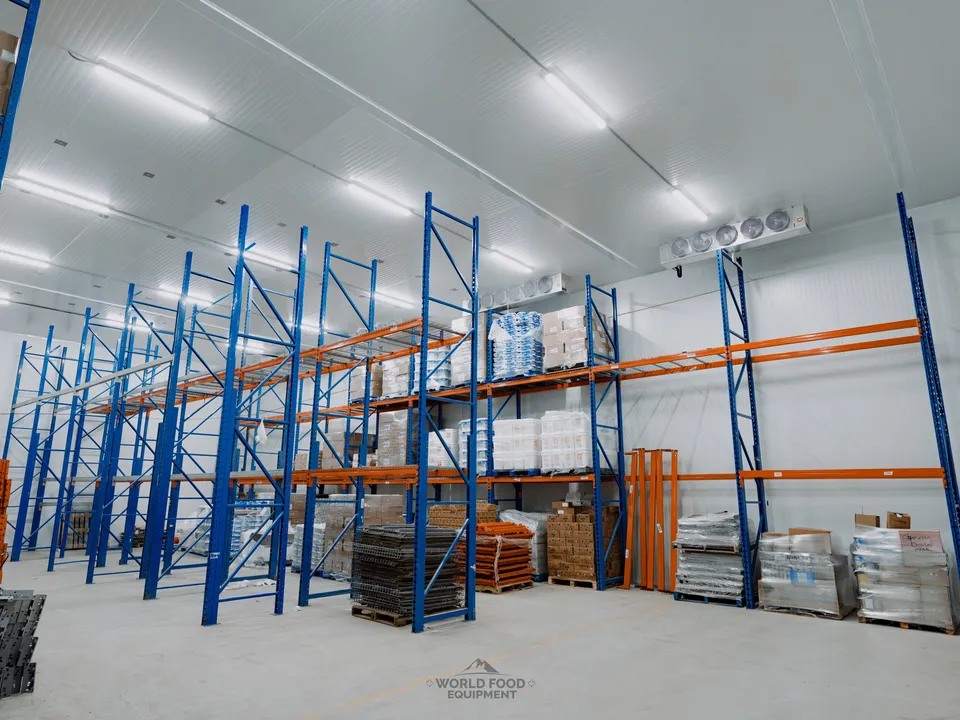 Atlas Foods 3,000 sq ft walk-in cooler operational at day-30 handoff, blue and orange pallet racking floor to ceiling with early product on the lower tiers, ceiling-mounted evaporators visible above, specialty food distribution starting to move through the room, Toronto.