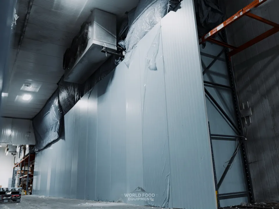 Rebuilt freezer wall at CJR Grocers from inside the envelope, ceiling-mounted evaporator running above the new panel section, refrigeration recommissioned on the rebuilt 140 ft section while the rest of the project continues in phases.