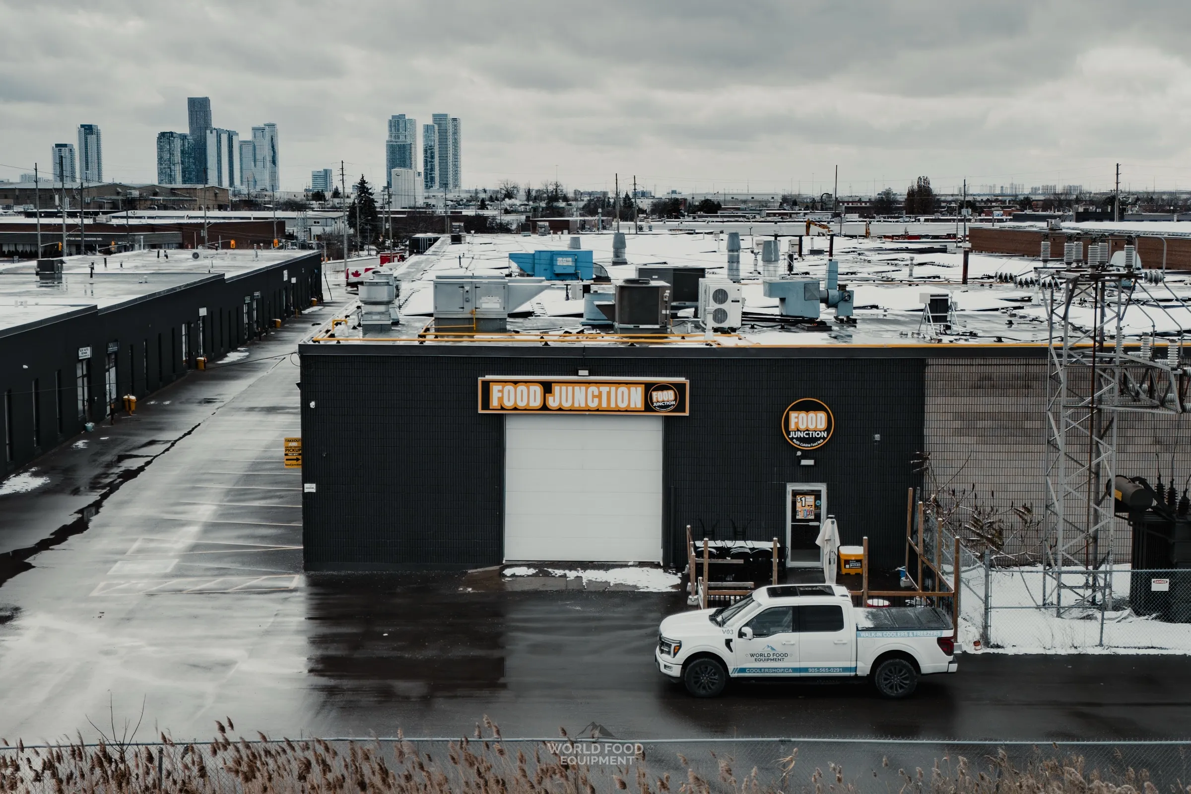 Food Junction Toronto restaurant walk-in cooler install video poster, exterior of the building with WFE truck on site and downtown Toronto skyline behind it.