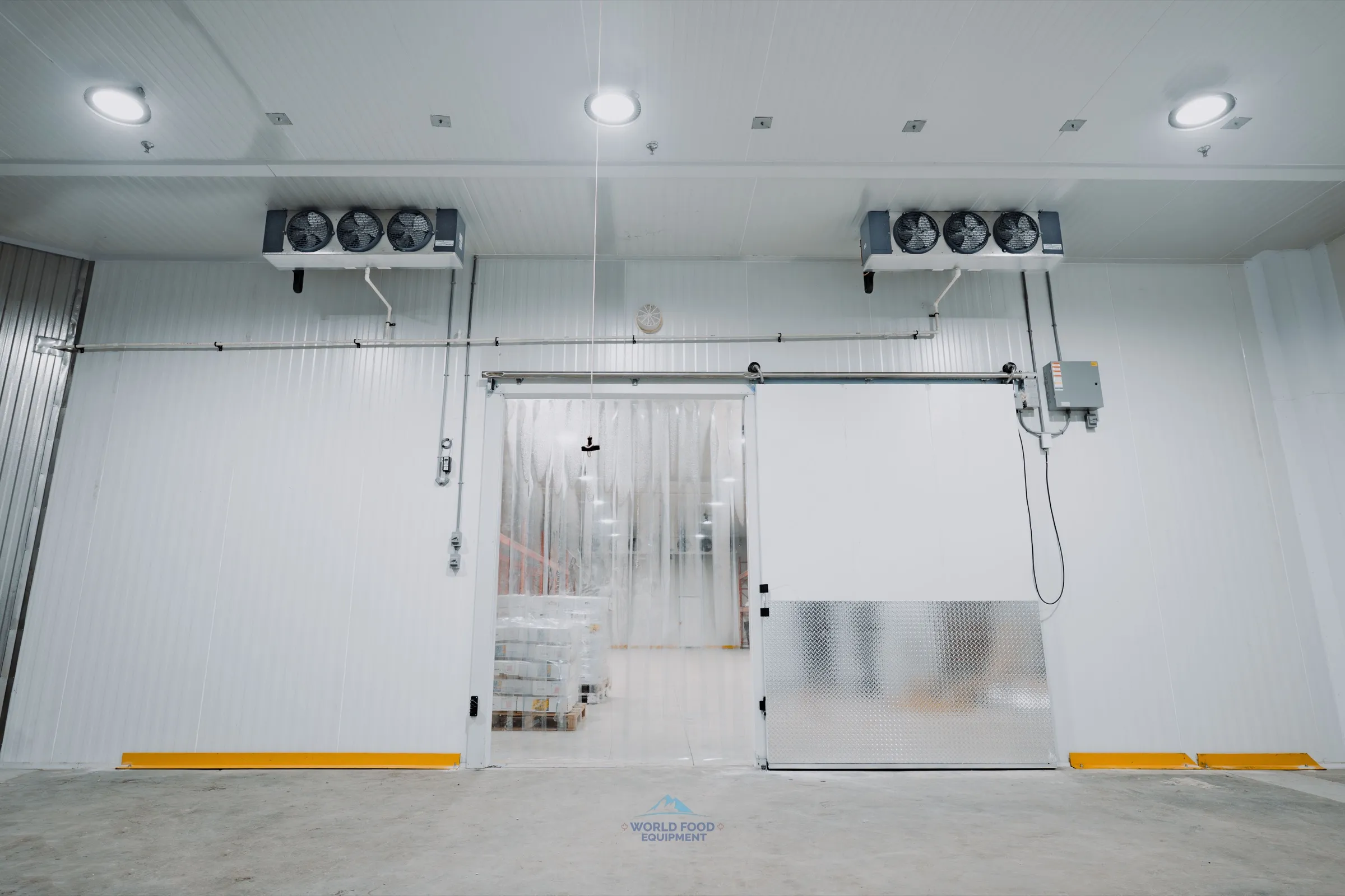 Finished 10,000 sq ft walk-in freezer at the halal meat processor with dual ceiling evaporators, sliding door open showing stocked pallets, KeepRite compressors and K2 monitoring throughout.