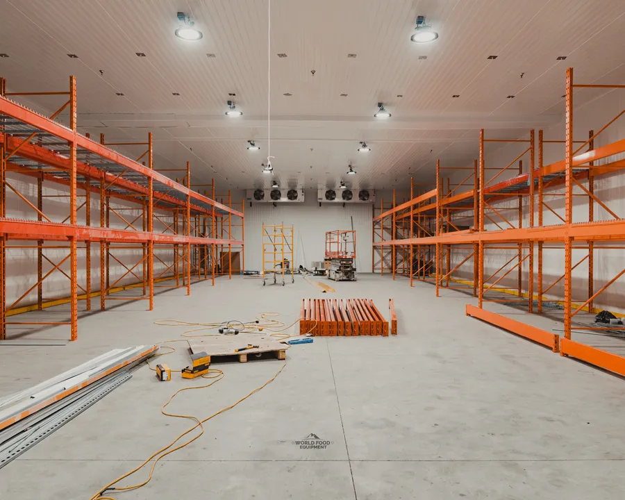 Walk-in freezer mid-install at an Ontario meat-processing facility, panels framed and refrigeration roughed in before commissioning, World Food Equipment crew