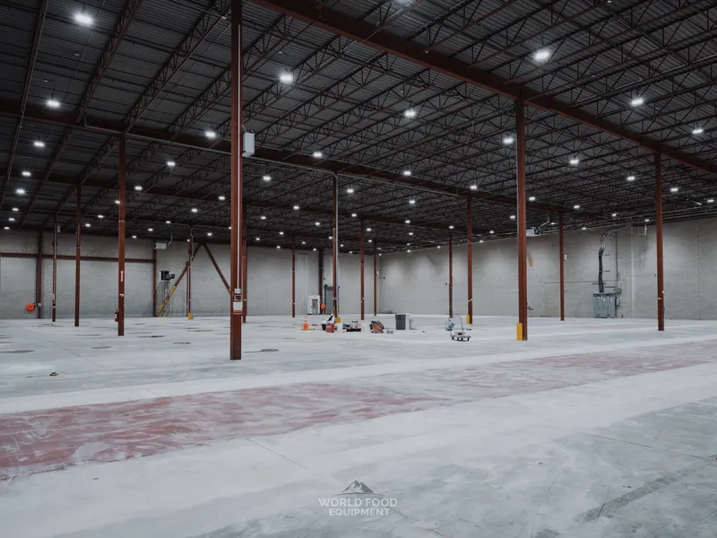 Cleared Longo's distribution floor in Scarborough with faint orange demarcation marks visible on the polished concrete where refrigerated display cases used to sit, structural columns and ceiling structure above.