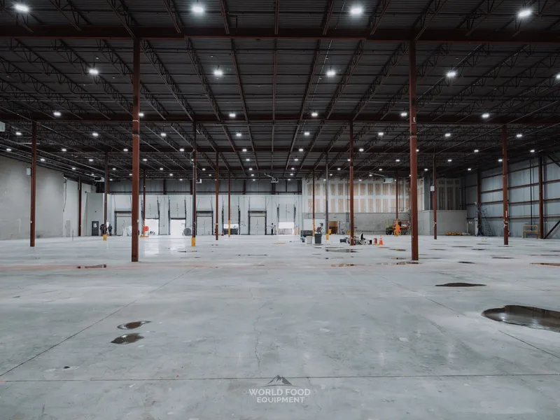 WFE crew walking the cleared Longo's distribution floor in Scarborough for final sign-off, two workers visible in the distance, polished concrete floor cleared of refrigeration, structural columns running across the space.