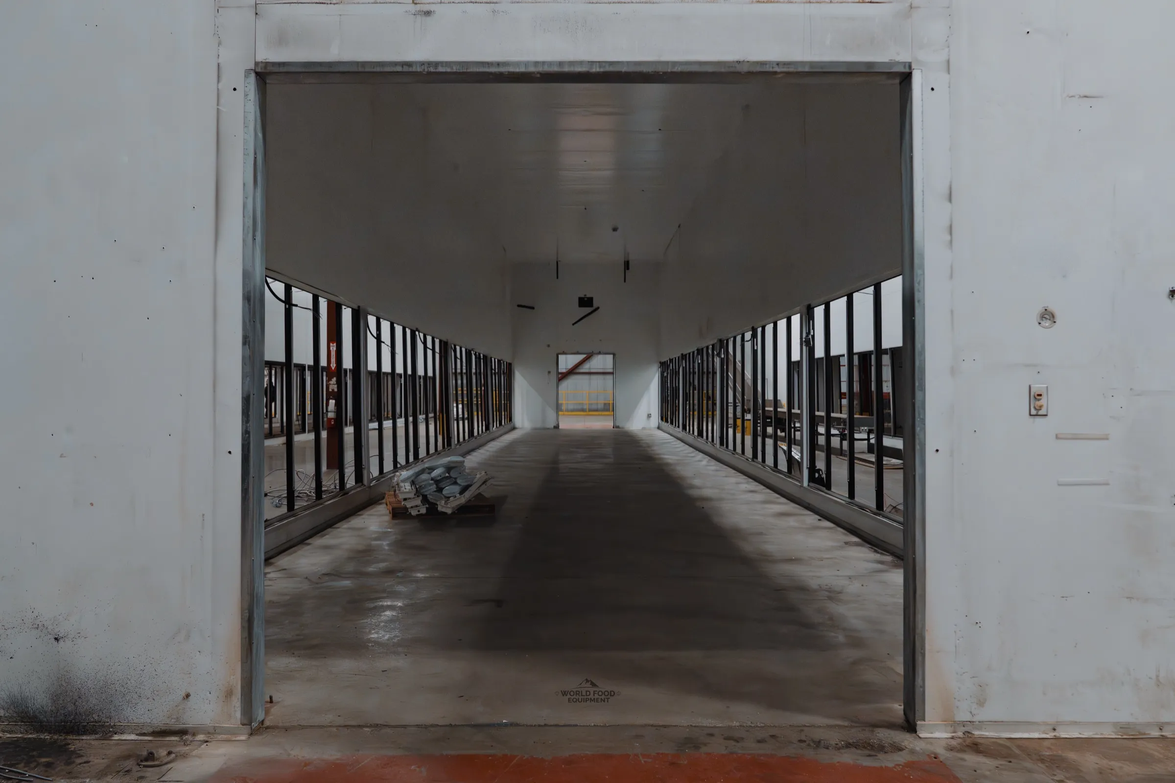 Cinematic doorway view into Longo's mid-build cooler corridor.