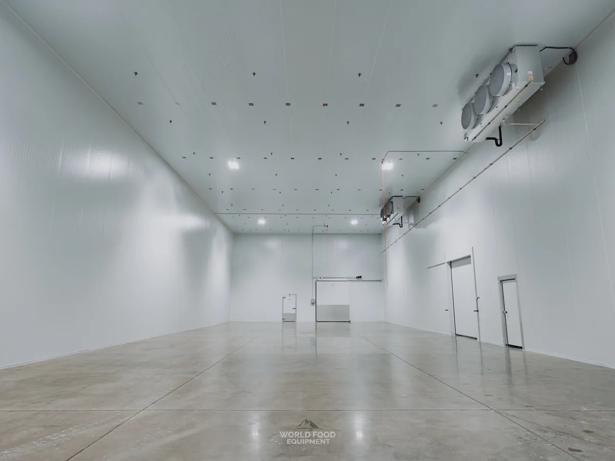 Cathedral-scale interior of the Pacer Air Freight medical-grade cold storage envelope in Mississauga: multi-zone ceiling-mounted KeepRite evaporators distributed along the far and right walls, white insulated panel walls and ceiling clean across the 10,000 sq ft pharmaceutical envelope, polished concrete floor reflecting the structure.
