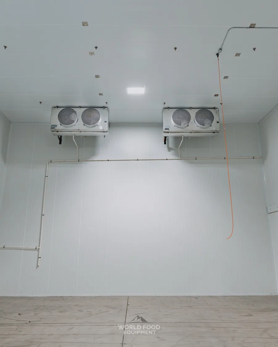 Mid-size industrial cold storage room with dual two-fan ceiling-mounted KeepRite evaporators on opposing walls and finished white insulated panels, Pacer Air Freight install, Ontario, World Food Equipment
