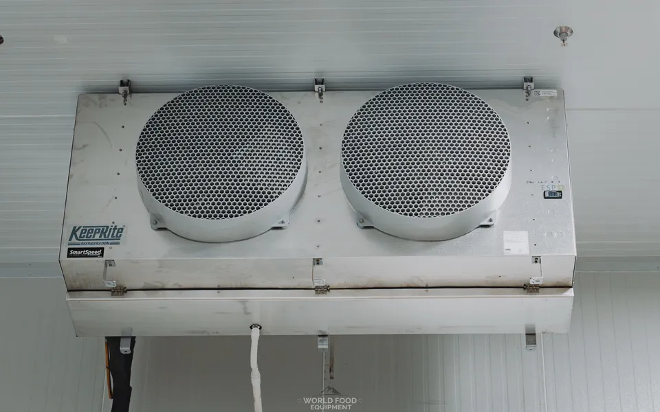 KeepRite SmartSpeed evaporator unit ceiling-mounted in a finished operational walk-in, brand decal visible, refrigerant line set with foam insulation, Pacer Air Freight install, Ontario, World Food Equipment.