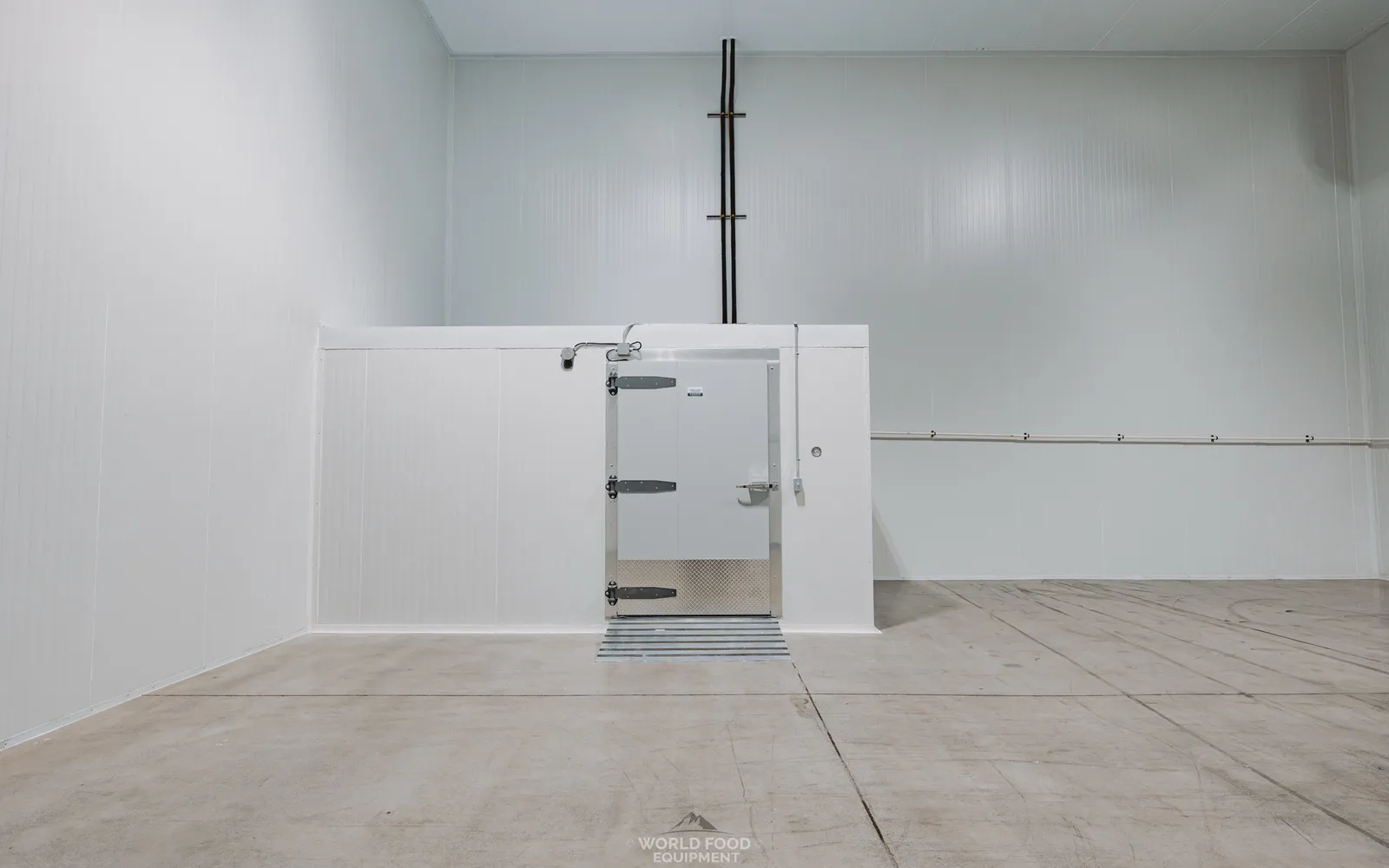 Finished commercial walk-in cooler envelope with centered white insulated swing door, diamond-plate kickplate, heavy-duty hinges, white panel walls falling away on both sides, Pacer Air Freight install, Ontario, World Food Equipment