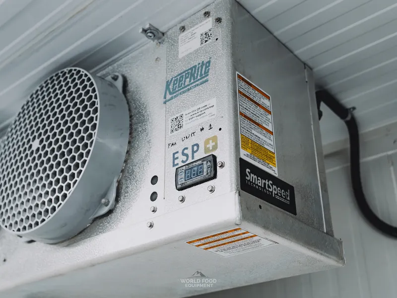 Angled close-up of a KeepRite ESP+ SmartSpeed control panel at the Pacer Air Freight medical-grade cold storage in Mississauga, KeepRite Refrigeration logo prominent, ESP+ model badge and SmartSpeed control display visible, evaporator fan grille at the left, "FAN UNIT" label.