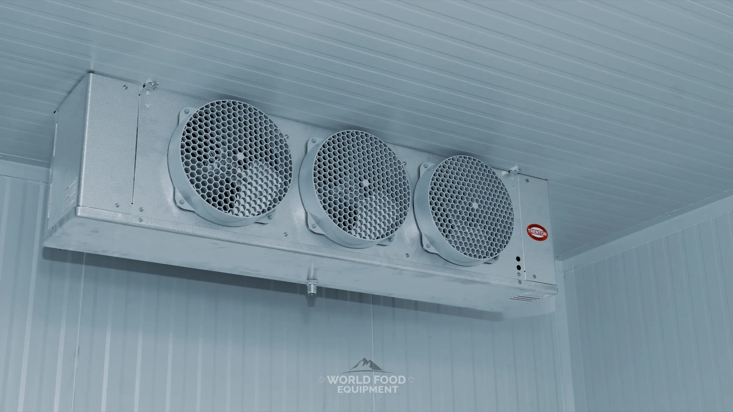 Trenton three-fan evaporator ceiling-mounted inside a finished white-panel walk-in at the Progress Avenue install in Ontario, condensate drain fitting visible on the underside, World Food Equipment
