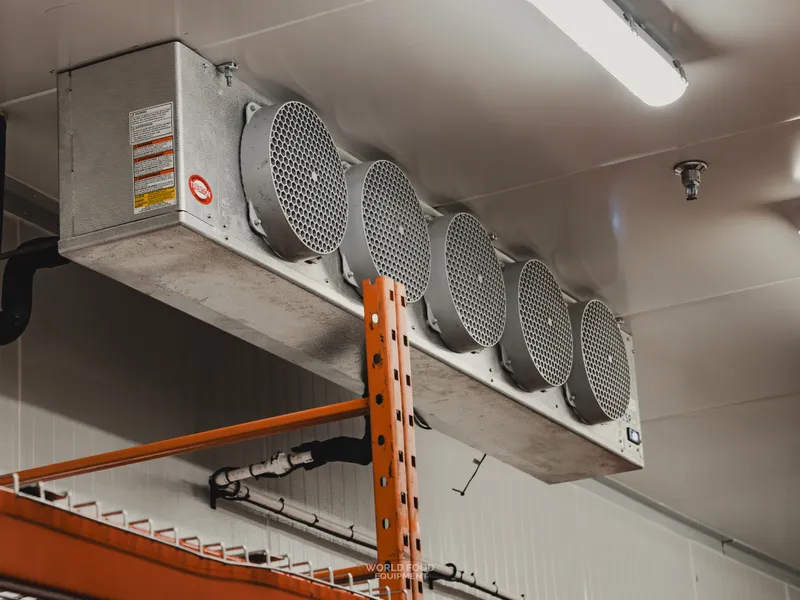 Five-fan KeepRite ceiling-mounted evaporator inside the Stainless Steel walk-in cooler, visible red KeepRite badge on the housing, insulated lines below.