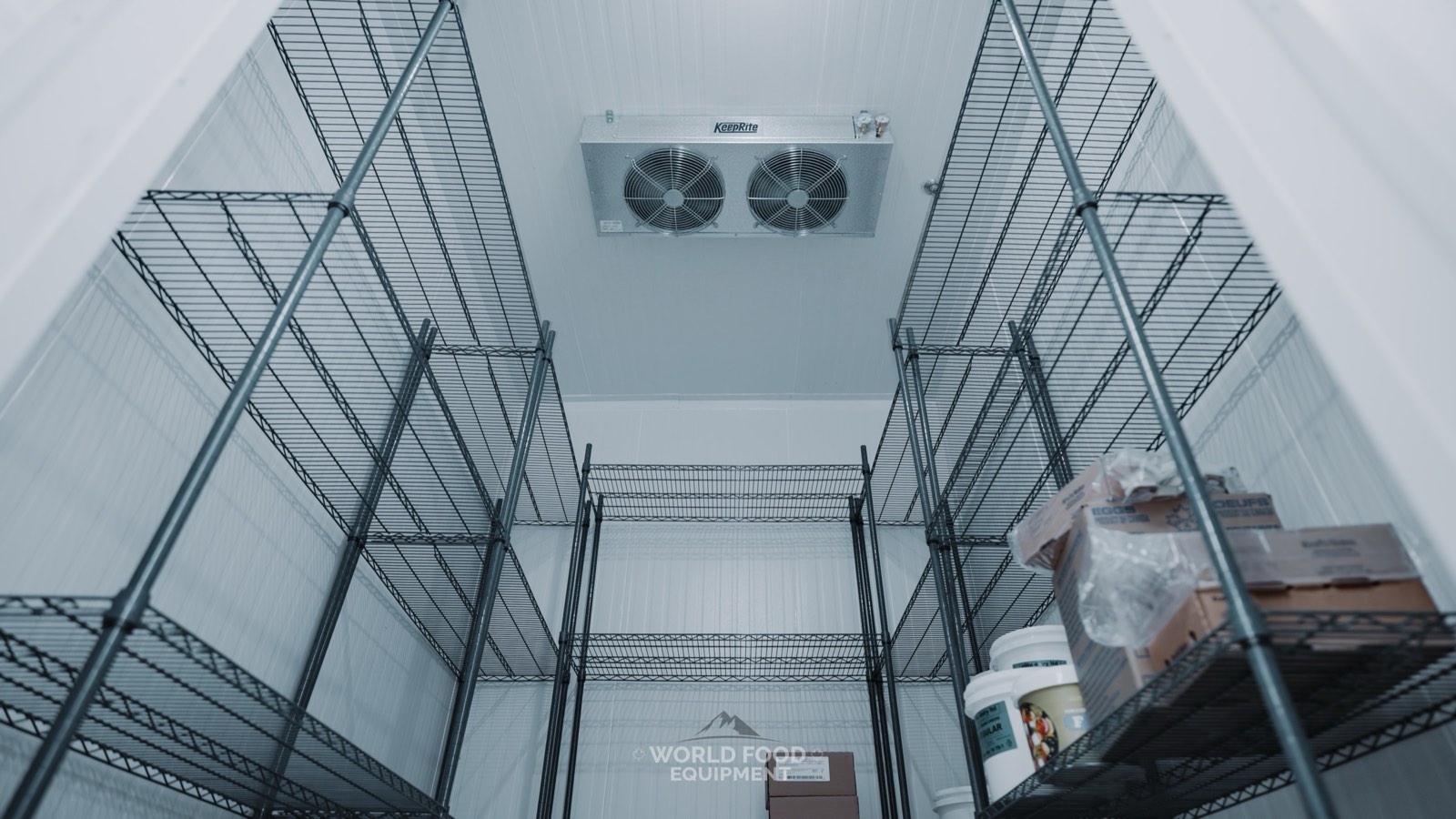 Finished restaurant walk-in cooler interior at a WFE install in Toronto, wire shelving along both walls and a ceiling-mounted twin-fan evaporator