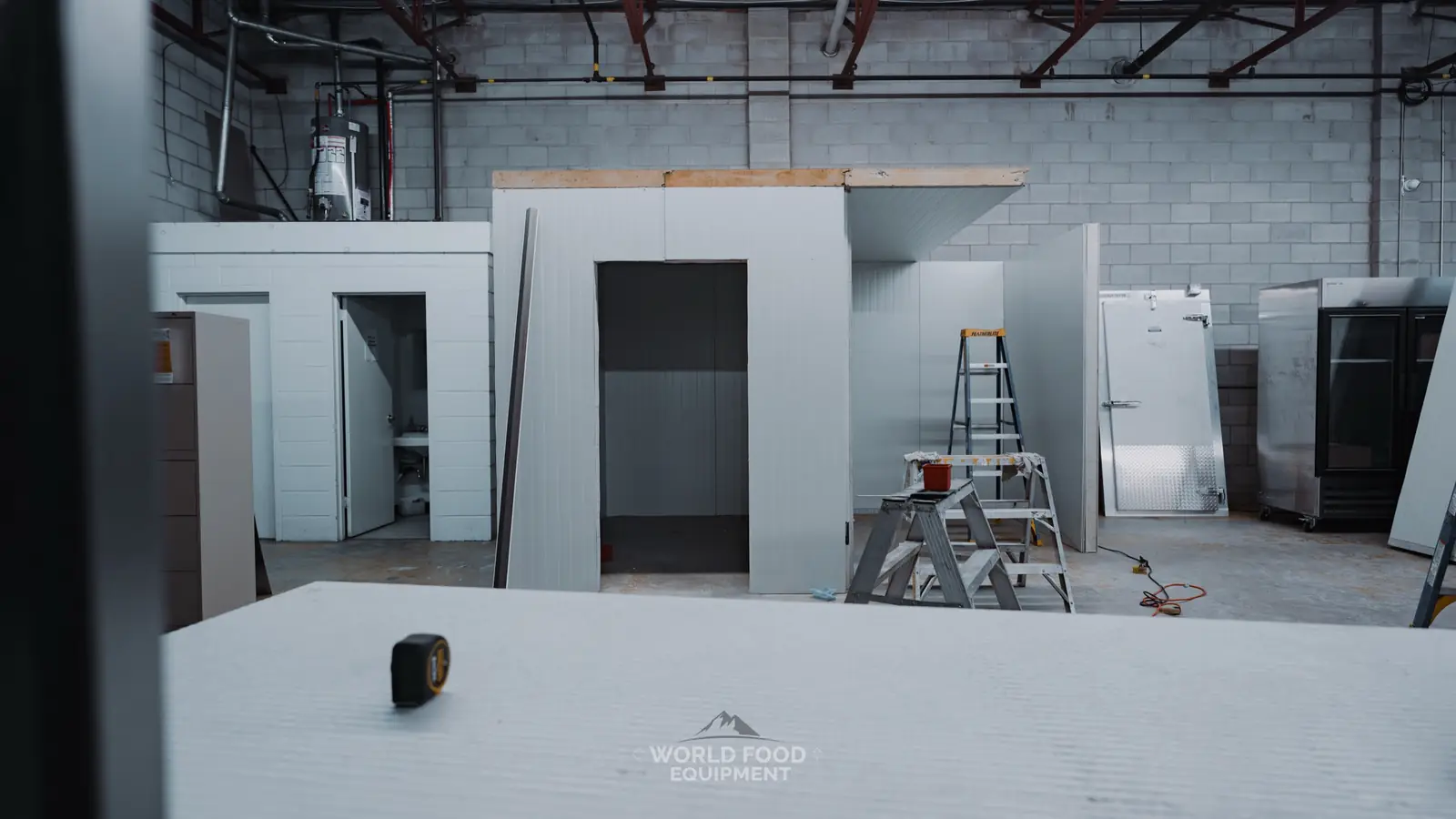 Walk-in cooler installation in progress at an Ontario site, insulated panels partly assembled with the door opening framed and install tools staged