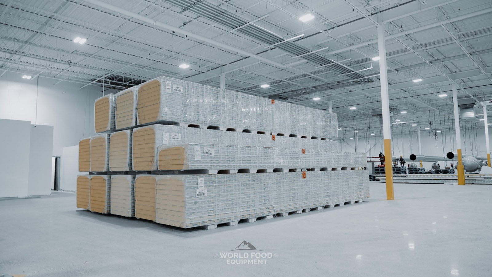 Pallets of shrink-wrapped insulated walk-in panels staged for assembly at a World Food Equipment cold storage install in Ontario