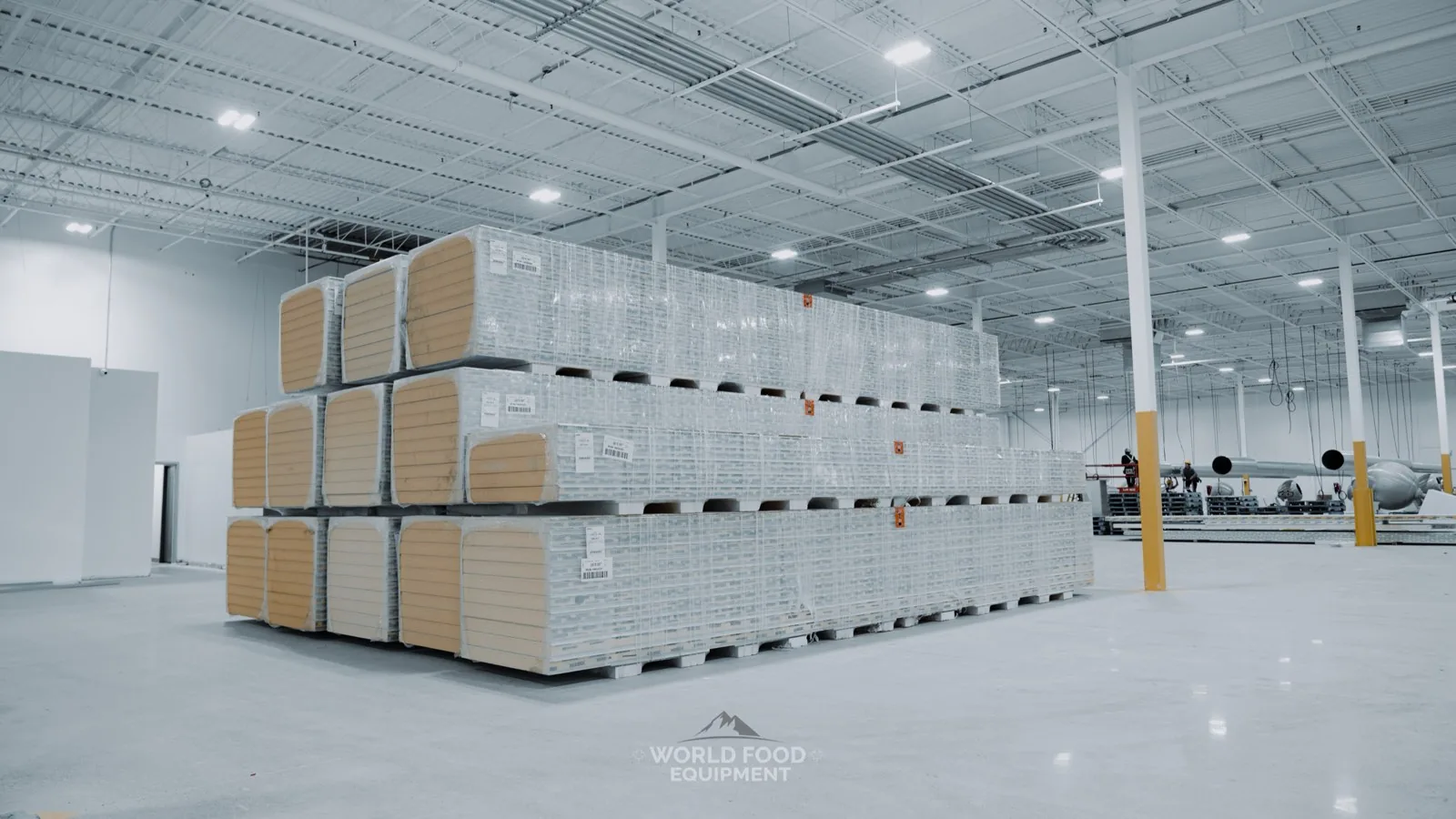 Pallets of shrink-wrapped insulated walk-in panels staged for assembly at a World Food Equipment cold storage install in Ontario