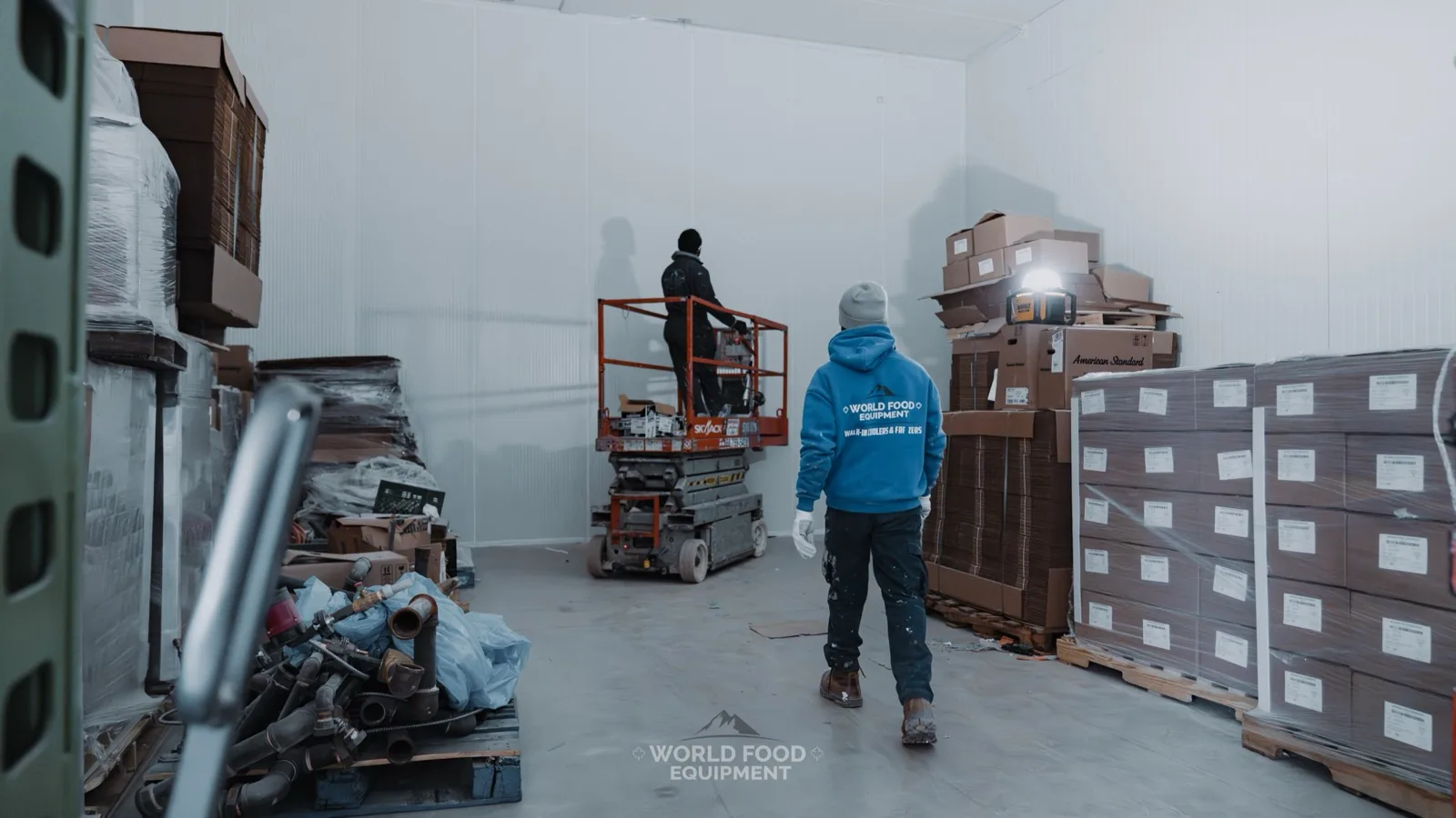 World Food Equipment crew assembling a large indoor walk-in cold storage room from insulated panels using a scissor lift at an Ontario install